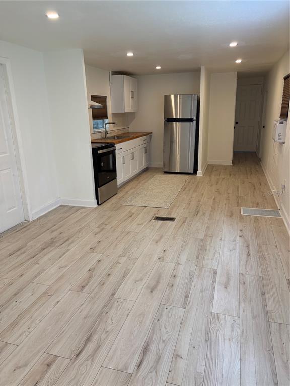 A kitchen features light wood-look flooring, white cabinets, a butcher block countertop, and stainless appliances — 24739 AUDREY ROAD, LAND O LAKES, FL