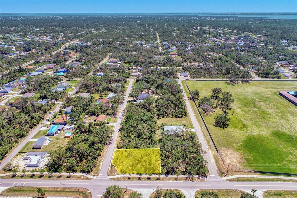 An aerial view shows a vacant, rectangular lot highlighted in yellow along a paved road — 17919 TOLEDO BLADE BOULEVARD, PORT CHARLOTTE, FL