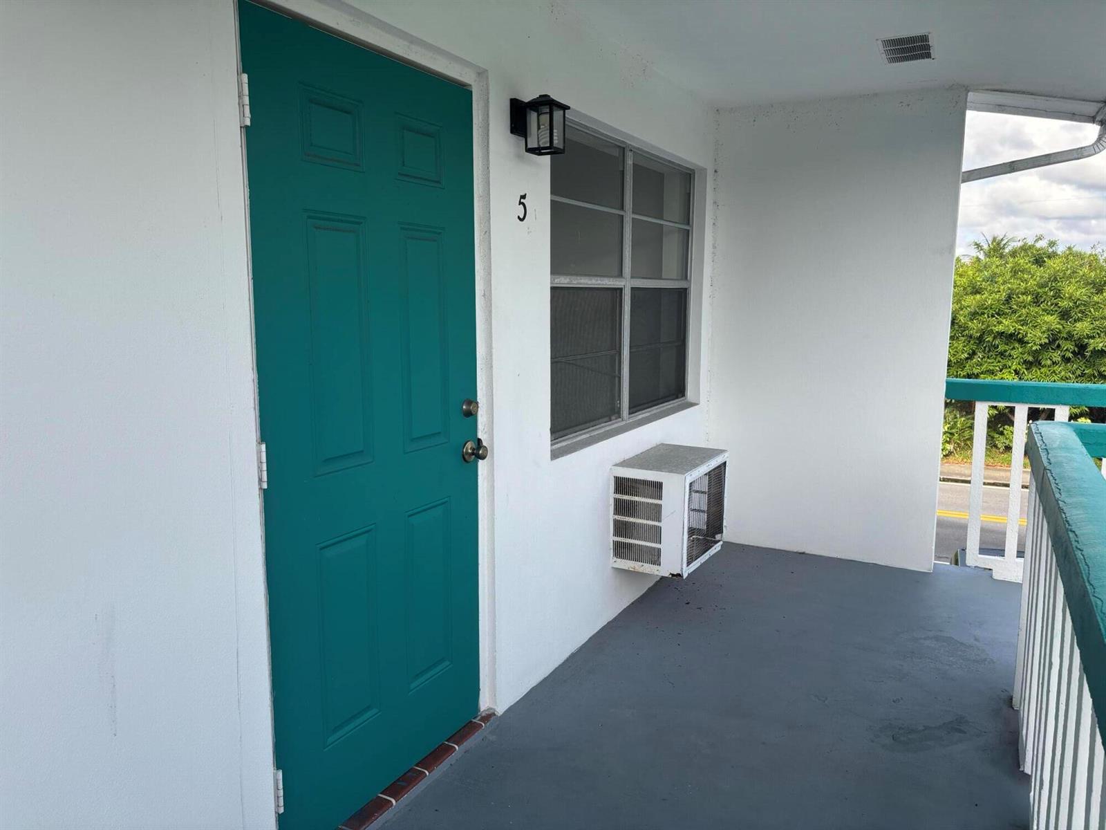 A teal door labeled number five sits on a balcony next to a window unit — 1111 N Federal Highway # 5, FL 33460, FL