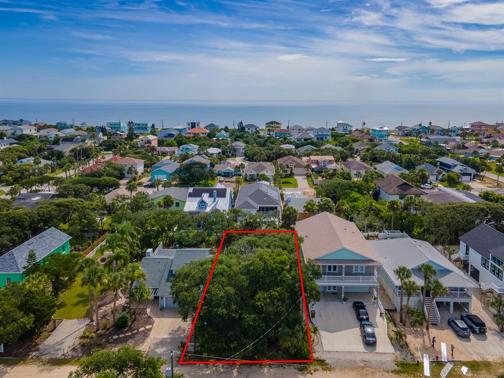 An aerial view shows a vacant, tree-covered residential lot outlined in red between two houses — 2721 S JOHN BULL STREET, FLAGLER BEACH, FL