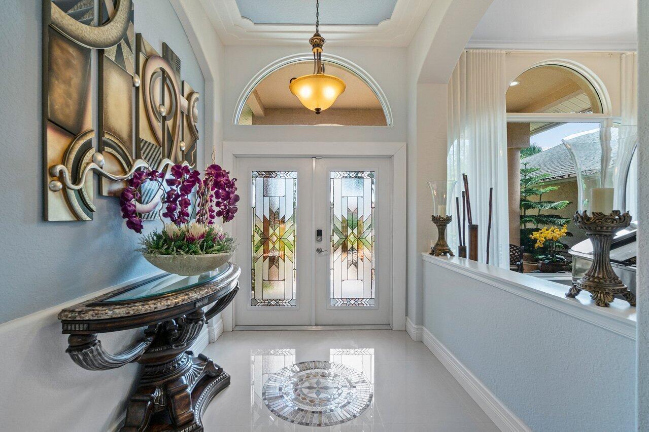 A bright foyer features a decorative console table, stained glass double doors, and tile flooring — 1265 Longlea Terrace, Wellington FL 33414, WELLINGTON, FL
