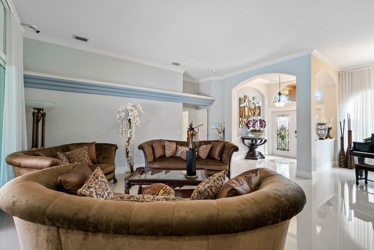 A living room features curved brown sofas, a glass-topped coffee table, and light blue walls — 1265 Longlea Terrace, Wellington FL 33414, WELLINGTON, FL