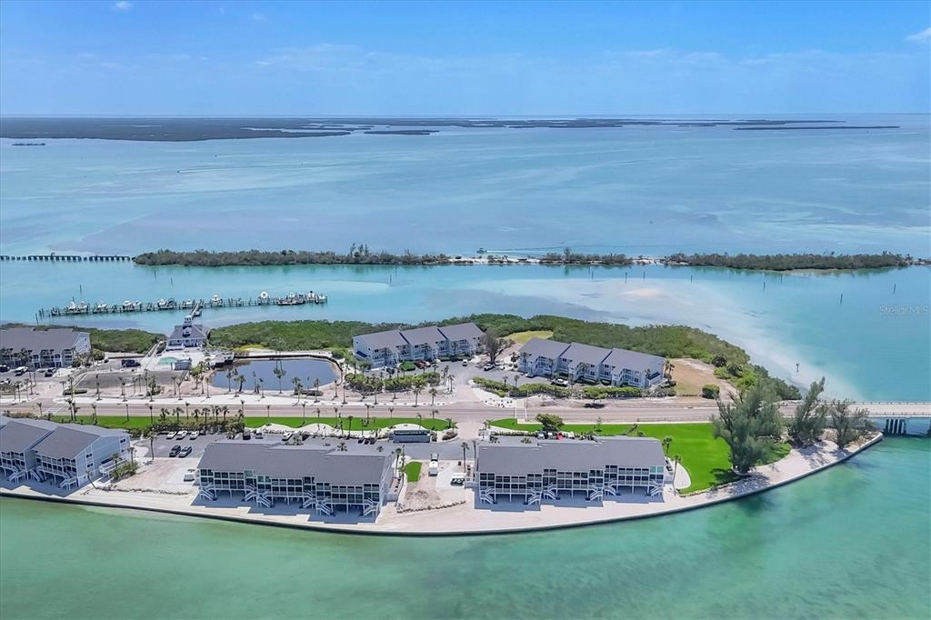 An aerial view shows waterfront condominiums surrounded by turquoise water and a small island — 6010 BOCA GRANDE CAUSEWAY UNIT C26, BOCA GRANDE, FL