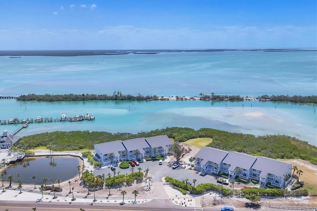 An aerial view shows two multi-story buildings near a bay with a boat dock — 6010 BOCA GRANDE CAUSEWAY UNIT C26, BOCA GRANDE, FL