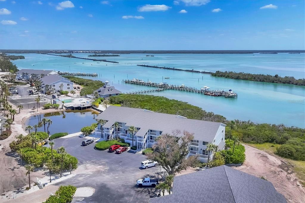 An aerial view shows a multi-story apartment building, a parking lot, and a boat dock — 6010 BOCA GRANDE CAUSEWAY UNIT C26, BOCA GRANDE, FL
