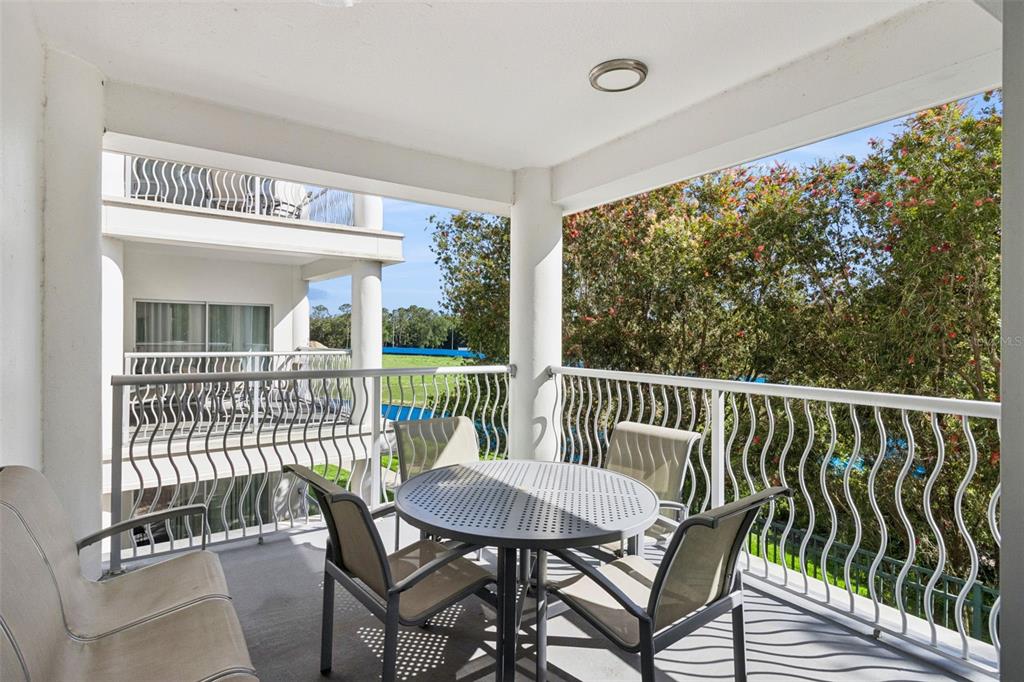 A covered balcony features a round table with four chairs and white metal railings — 225 CELEBRATION PLACE UNIT 216, CELEBRATION, FL