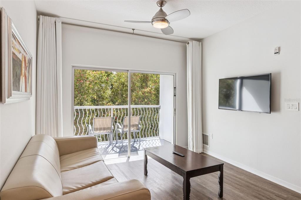 A living room features a beige sofa, a coffee table, a wall-mounted television, and a balcony — 225 CELEBRATION PLACE UNIT 216, CELEBRATION, FL