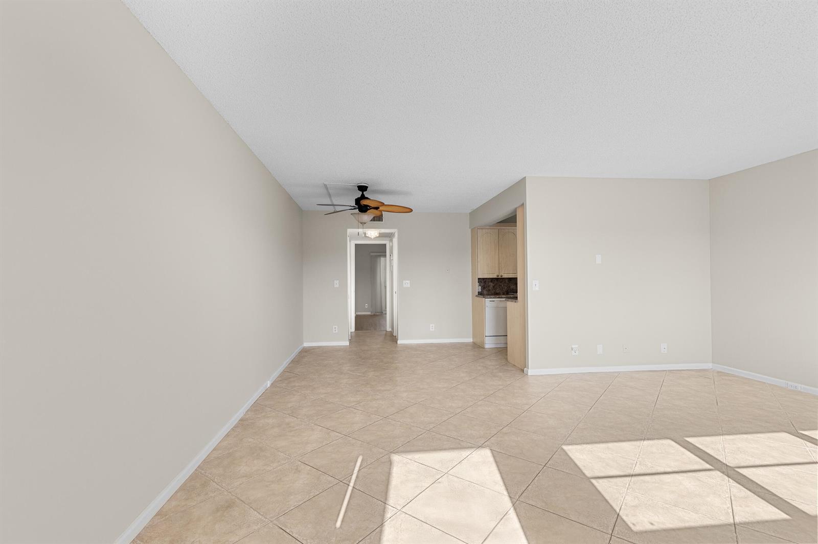 An empty living area features beige tile flooring, light-colored walls, and a ceiling fan — 3013 Wolverton A, Boca Raton FL 33434, BOCA RATON, FL
