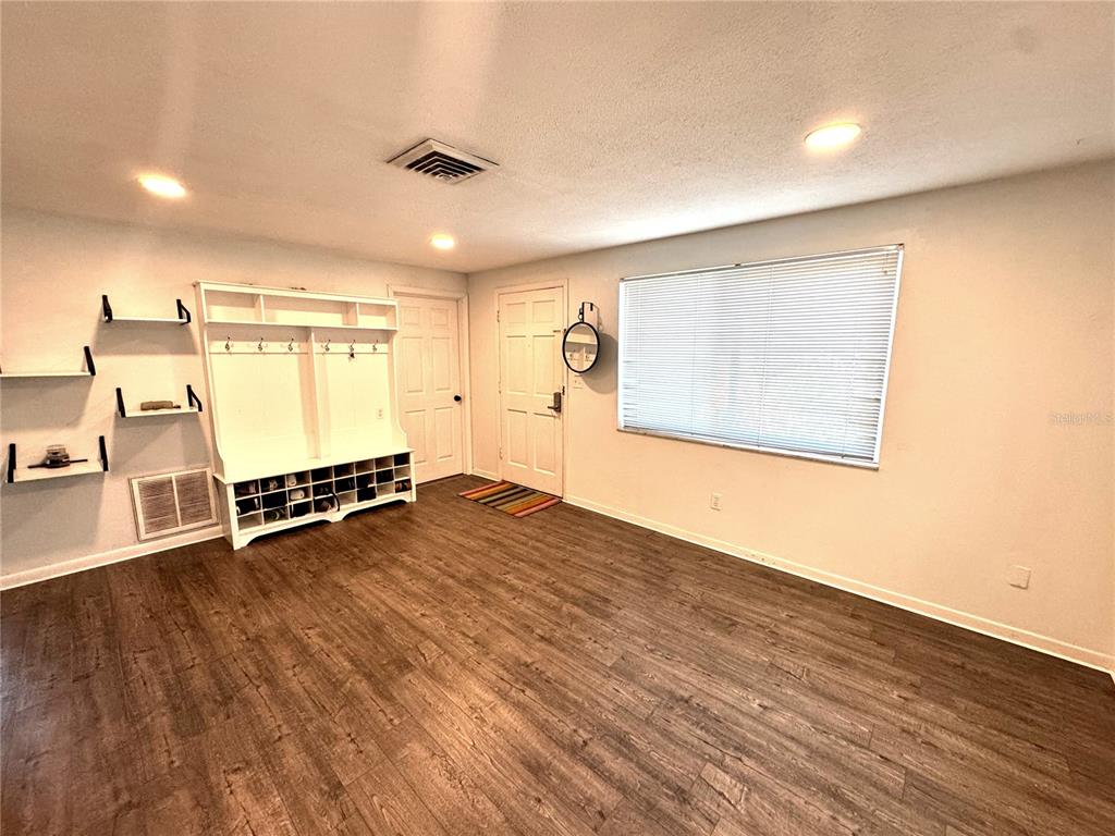 An entryway with wood-look flooring, a white mudroom bench, wall shelving, and a front door — 6550 3RD AVENUE S, ST PETERSBURG, FL