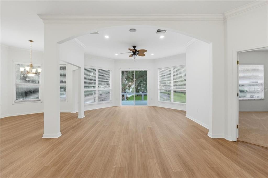 An open-concept living area features light wood-look flooring, white walls, and a large arched entryway — 6760 LAKE CLARK DRIVE, LAKELAND, FL