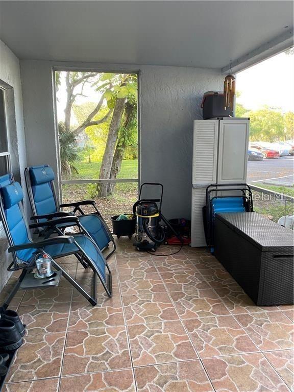 A screened-in porch features tiled flooring, two blue lounge chairs, and a storage cabinet — 2404 NORTHLAKE DRIVE NE UNIT 2404, SANFORD, FL