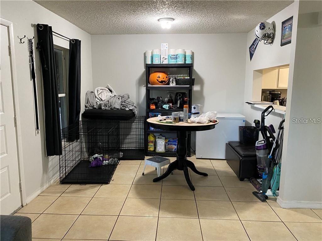 A dining area features tile flooring, a round table, a black shelving unit, and a crate — 2404 NORTHLAKE DRIVE NE UNIT 2404, SANFORD, FL