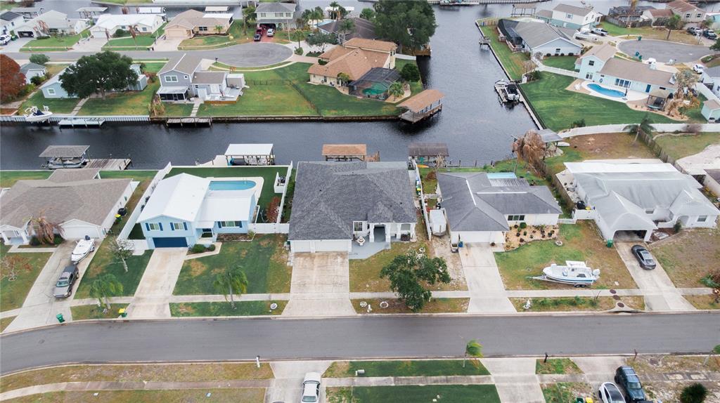An aerial view shows several waterfront houses with pools and boat docks along a canal — 2145 PORPOISE STREET, MERRITT ISLAND, FL