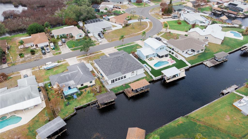 An aerial view shows waterfront houses with private docks and swimming pools along a canal — 2145 PORPOISE STREET, MERRITT ISLAND, FL