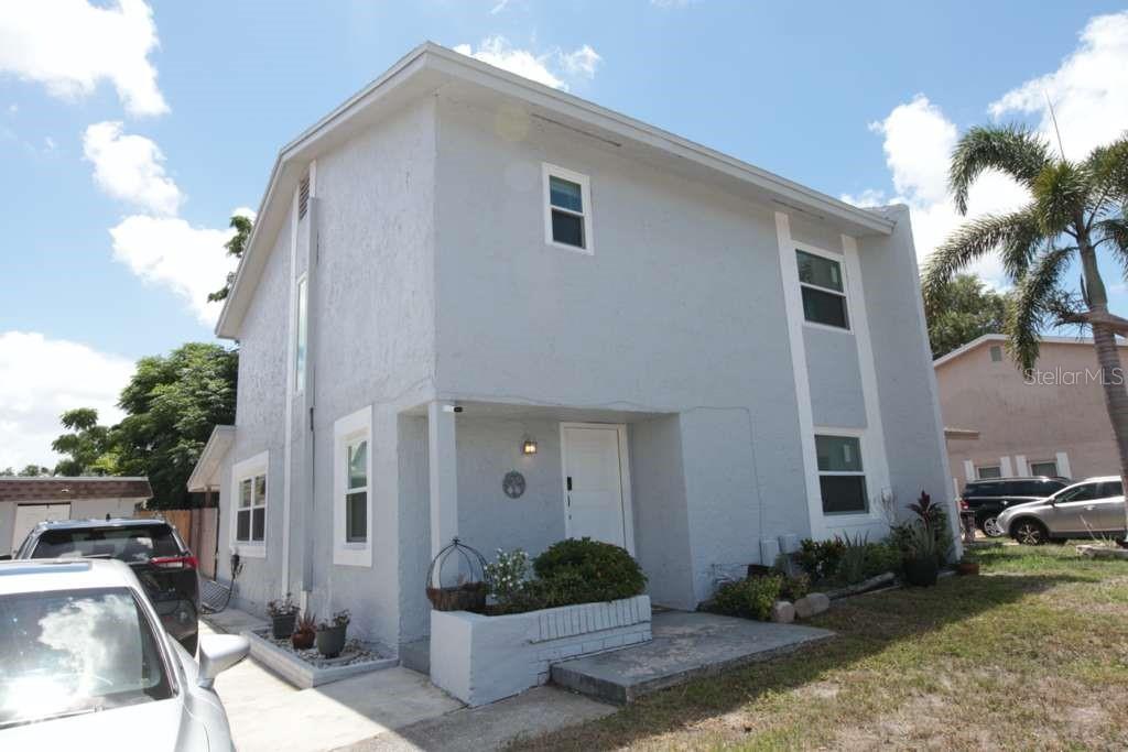 A two-story, light gray stucco house with a front entrance and a small garden bed — 2073 SAN SEBASTIAN WAY N, CLEARWATER, FL