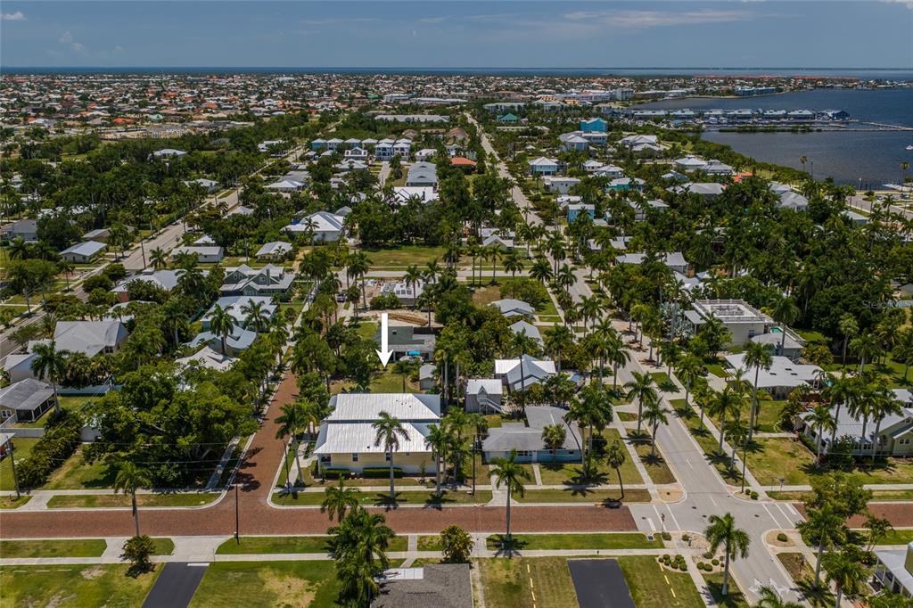 An aerial view shows a yellow house with a metal roof in a coastal neighborhood — 610 TRABUE AVENUE, PUNTA GORDA, FL
