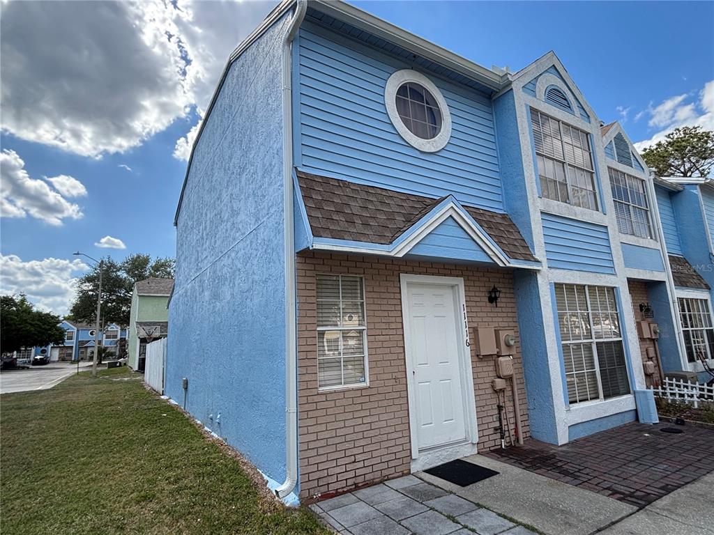 A two-story townhouse with blue siding, a brick facade, and a circular upper window — 11116 ALDERLY, ORLANDO, FL