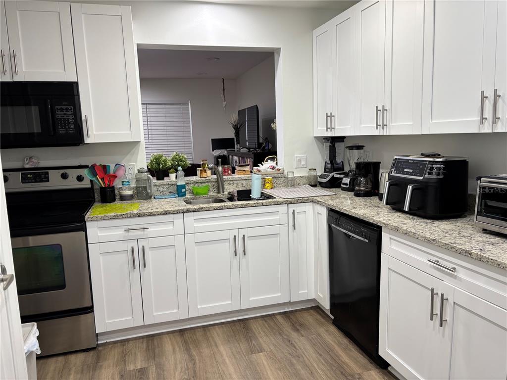 A kitchen features white cabinets, granite countertops, stainless steel appliances, and a black dishwasher — 11116 ALDERLY, ORLANDO, FL