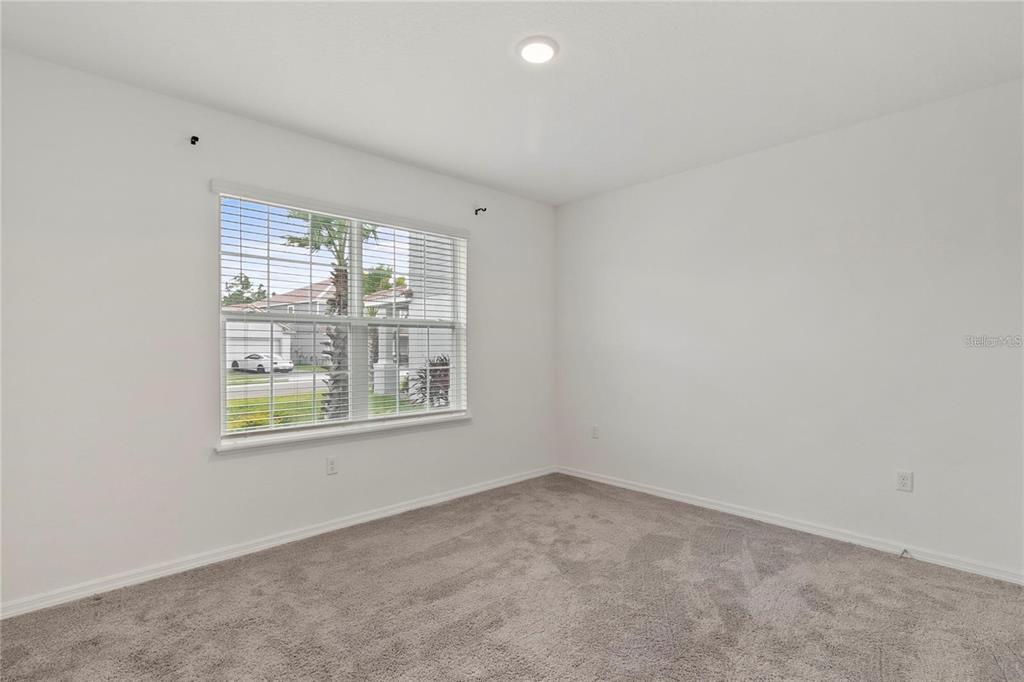 An empty bedroom features white walls, gray carpeting, a single window, and a ceiling light — 1154 OAK BLUFF DRIVE, DAVENPORT, FL