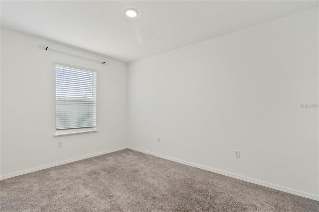An empty bedroom features white walls, gray carpeting, a single window, and recessed lighting — 1154 OAK BLUFF DRIVE, DAVENPORT, FL