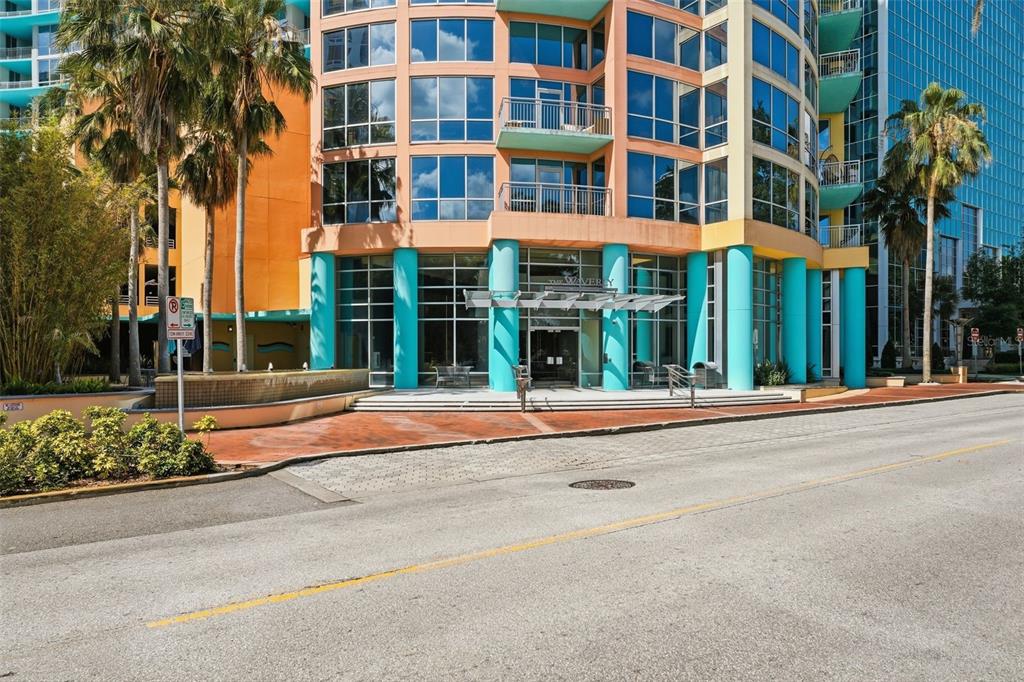 The exterior of a multi-story apartment building features orange walls, turquoise columns, and palm trees — 322 E CENTRAL BOULEVARD UNIT 912, ORLANDO, FL