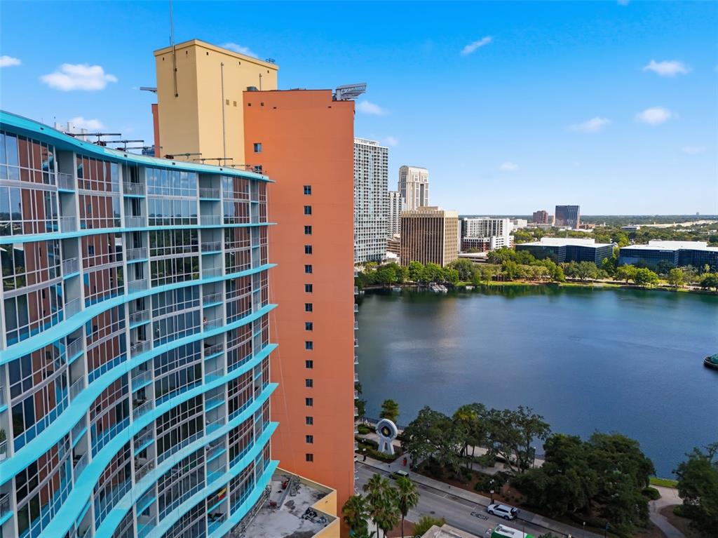 An aerial view shows a tall, multi-colored apartment building overlooking a lake and city skyline — 322 E CENTRAL BOULEVARD UNIT 912, ORLANDO, FL