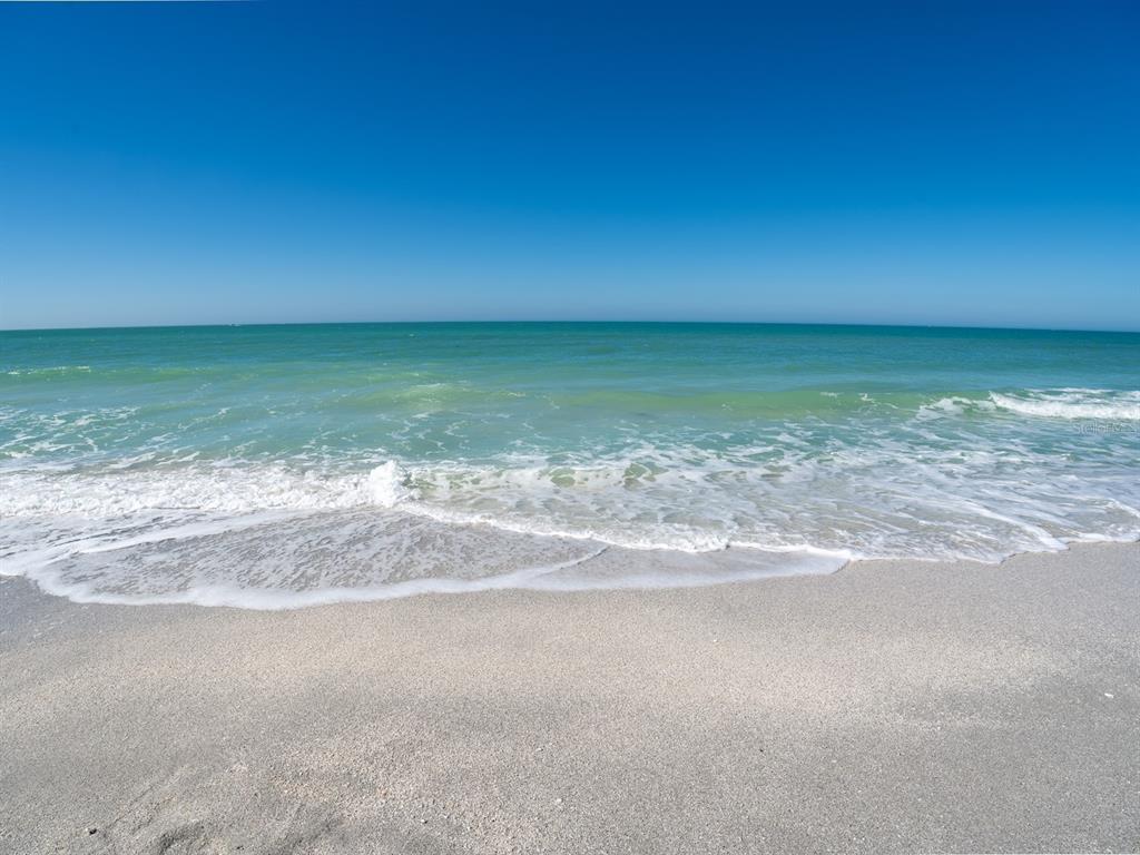 A view of a sandy beach with turquoise ocean waves meeting the shore under a sky — 1770 BENJAMIN FRANKLIN DRIVE UNIT 206, SARASOTA, FL