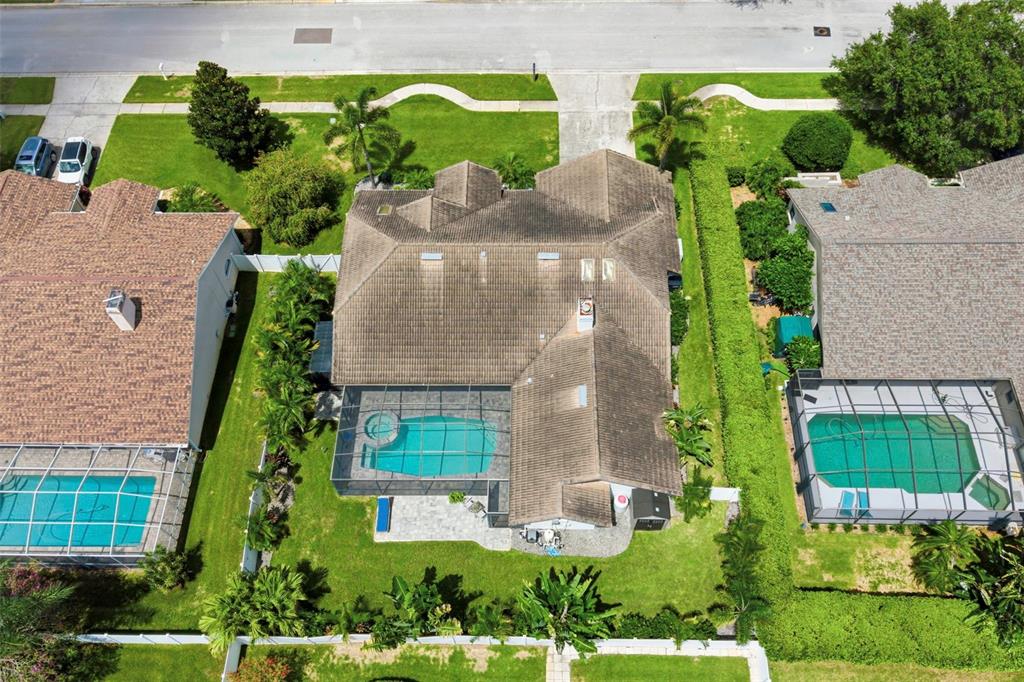 An aerial view shows a house with a tiled roof, a screened pool, and landscaping — 3347 LAKE SHORE LANE, CLEARWATER, FL