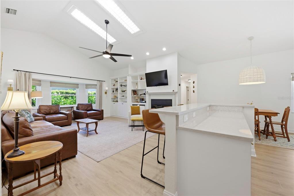 This open-concept living room features a vaulted ceiling, a fireplace, and a kitchen island — 3347 LAKE SHORE LANE, CLEARWATER, FL