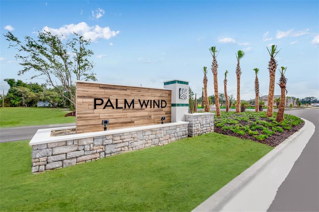 A stone and wood monument sign for Palm Wind stands on a grassy corner lot — 13667 TROPICAL BREEZE WAY, HUDSON, FL