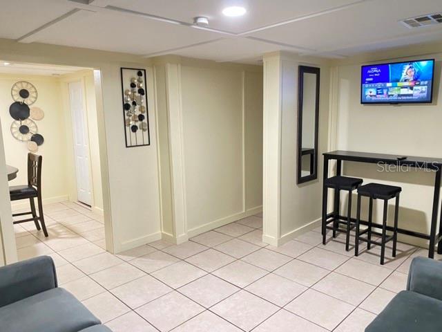 A basement living area features tiled floors, a wall-mounted television, and a high-top bar table — 26022 GLASGOW AVENUE, PUNTA GORDA, FL