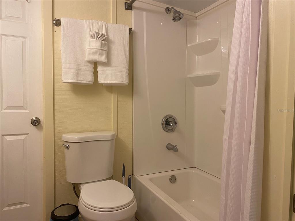 A bathroom features a white toilet, a shower-tub combination with white walls, and towels — 26022 GLASGOW AVENUE, PUNTA GORDA, FL