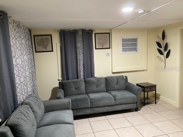 A living room features two gray sofas, tile flooring, and wall-mounted decor — 26022 GLASGOW AVENUE, PUNTA GORDA, FL