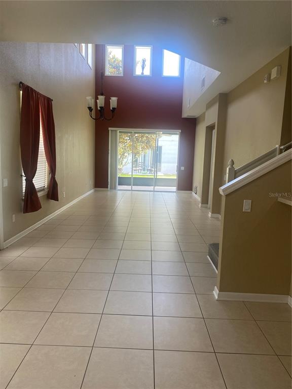 A spacious living area features high ceilings, tile flooring, a chandelier, and sliding glass doors — 1532 SHALLCROSS AVE, ORLANDO, FL