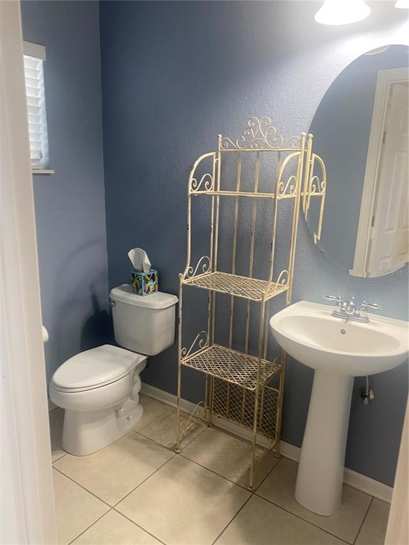 A bathroom features a pedestal sink, a toilet, and a decorative metal shelving unit — 1532 SHALLCROSS AVE, ORLANDO, FL