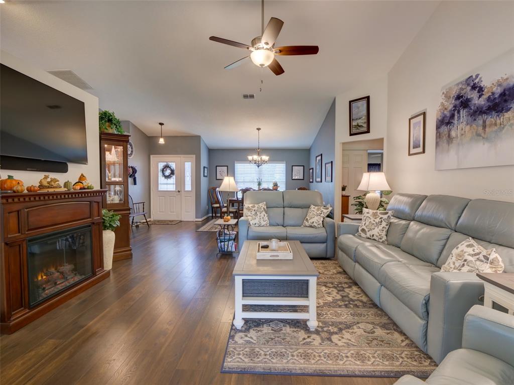 A living room features a fireplace, light blue leather sofas, and dark wood flooring — 4704 RIVER RIDGE DRIVE, LEESBURG, FL