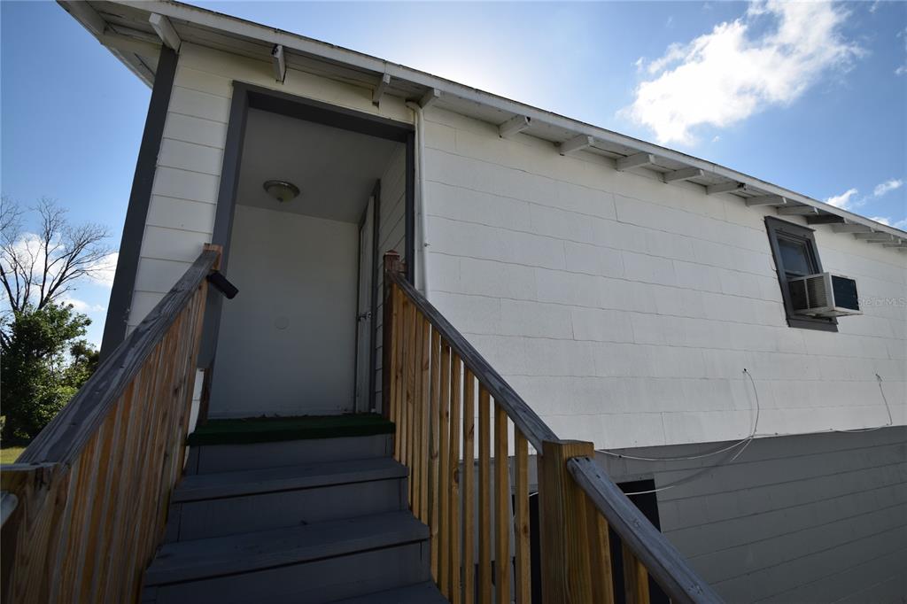 An exterior view of a white building with a wooden staircase leading to a doorway — 1060 E WABASH STREET UNIT 1060 1/2, BARTOW, FL