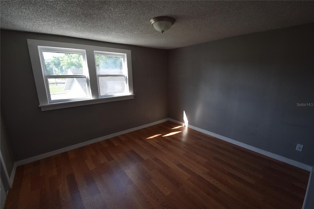 An empty bedroom features dark gray walls, wood-look flooring, and a double window — 1060 E WABASH STREET UNIT 1060 1/2, BARTOW, FL