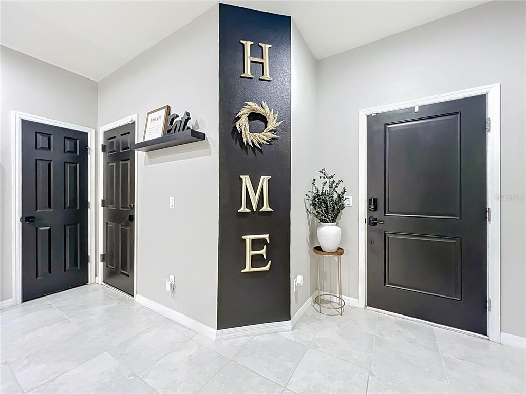 A foyer features a black accent wall with "HOME" lettering, two black doors, and tile flooring — 1084 PAVIA DRIVE, APOPKA, FL