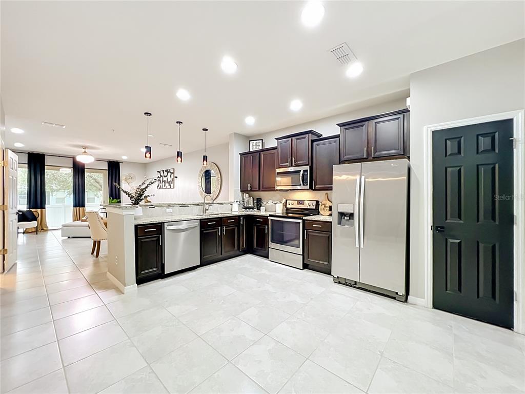 A kitchen with dark wood cabinets, stainless steel appliances, and light tile flooring — 1084 PAVIA DRIVE, APOPKA, FL
