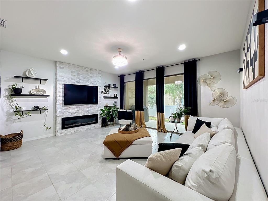 A living room features a stone fireplace, white sofa, and large sliding glass doors — 1084 PAVIA DRIVE, APOPKA, FL