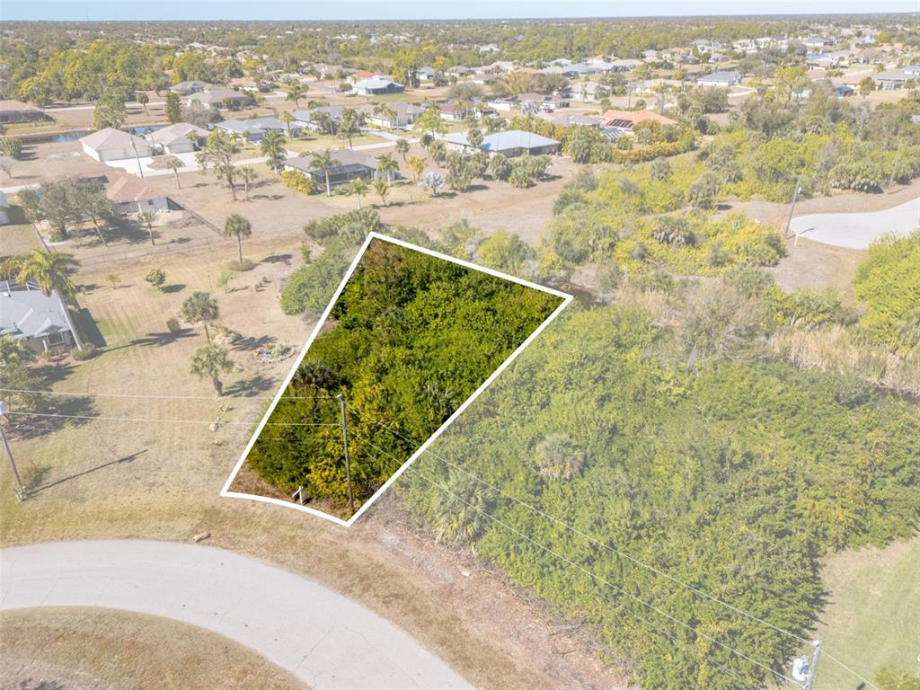 An aerial view shows a vacant, trapezoidal-shaped lot covered in dense vegetation — 132 CREVALLE ROAD, ROTONDA WEST, FL