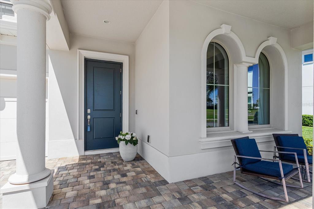A covered entryway features a dark blue door, arched windows, and two outdoor rocking chairs — 8222 TOPSAIL PLACE, WINTER GARDEN, FL