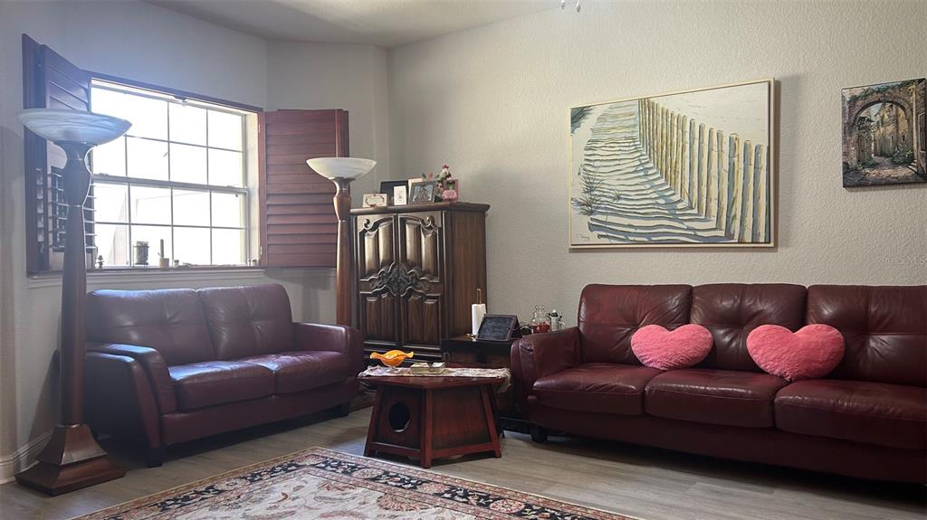 A living room features two red leather sofas, a wooden cabinet, and a large painting — 17334 PROMENADE DRIVE, CLERMONT, FL