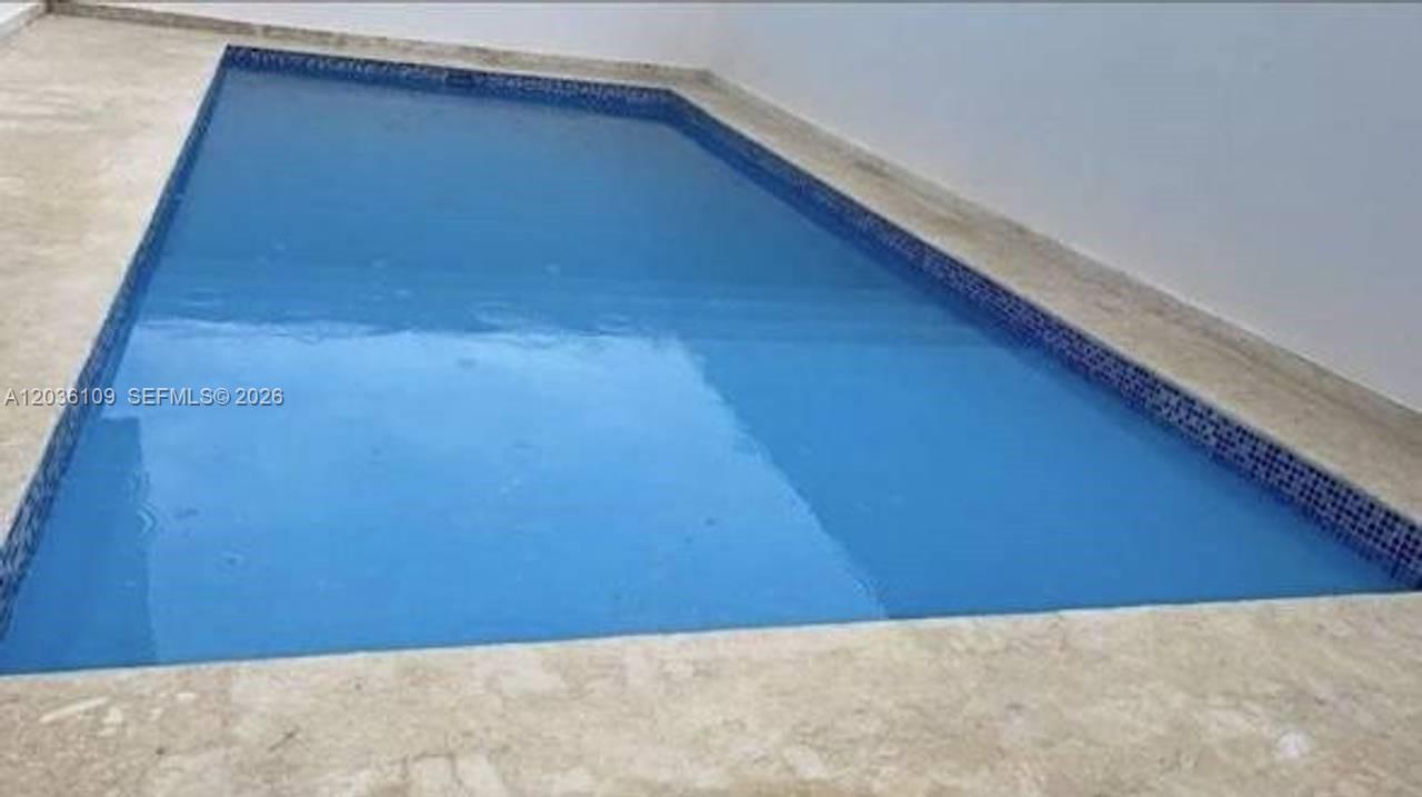 A rectangular swimming pool with blue tiles is surrounded by a light-colored stone deck — 0 Brisas, FL
