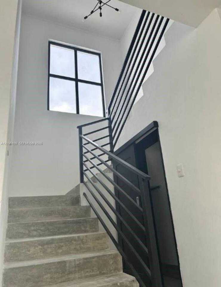 A staircase with concrete steps and a black metal railing leads upward toward a window — 0 Brisas, FL