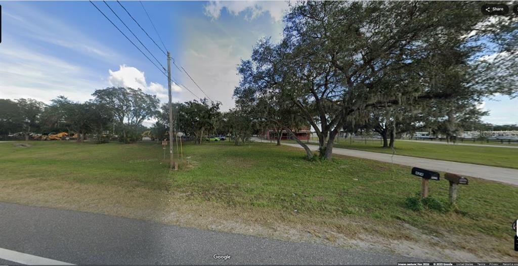 A grassy, tree-filled vacant lot sits beside a paved road with two mailboxes in front — N/A, POLK CITY, FL