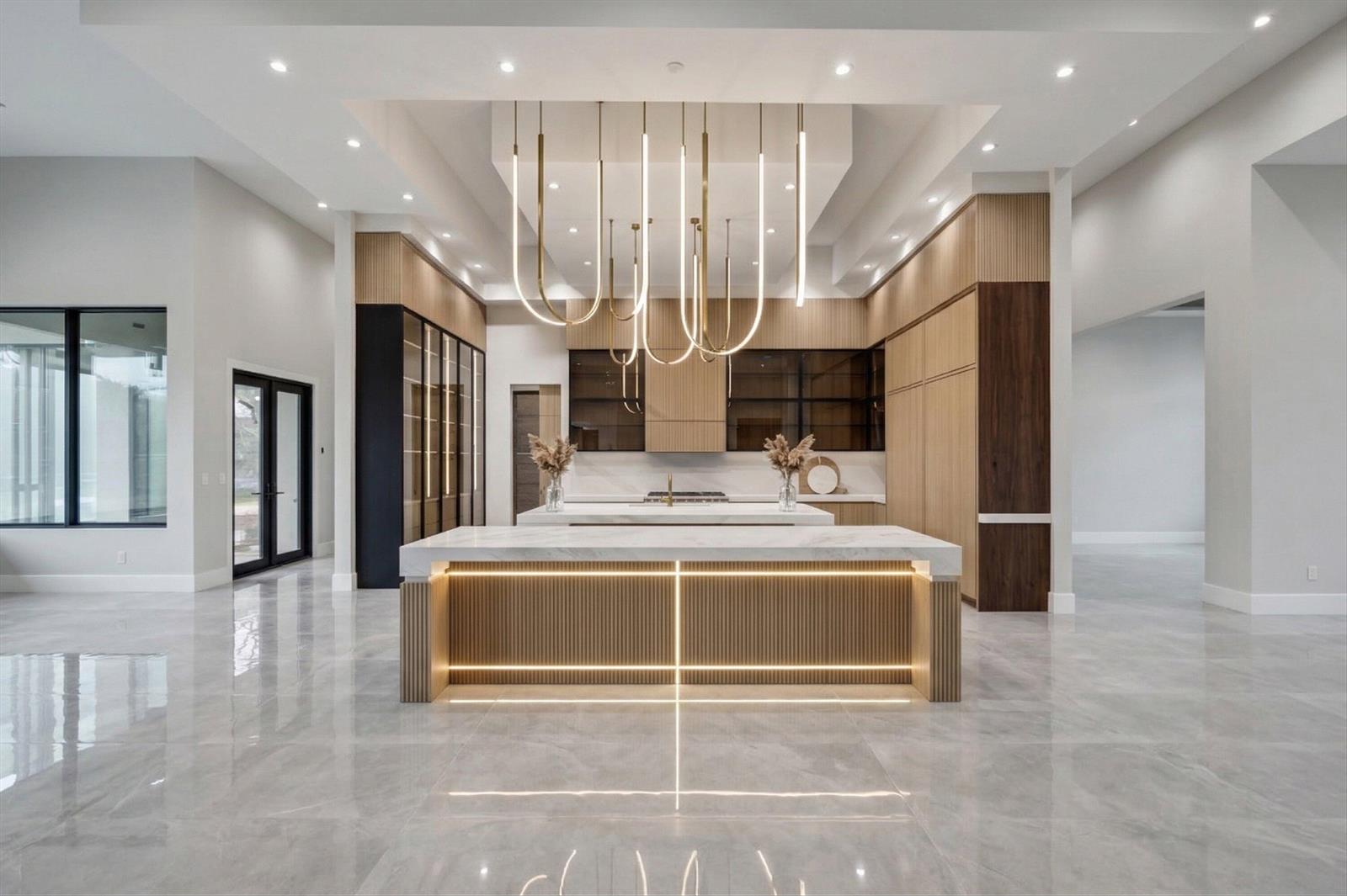 A modern kitchen features a marble-topped island, fluted wood cabinetry, and a large pendant light — 3905 Fieldview Way, Wellington FL 33414, WELLINGTON, FL