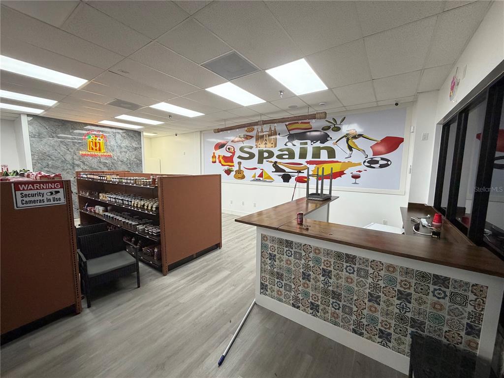 A retail space features a tiled service counter, shelving units, and a mural depicting Spain — 212 ST JOE PLAZA DRIVE, PALM COAST, FL