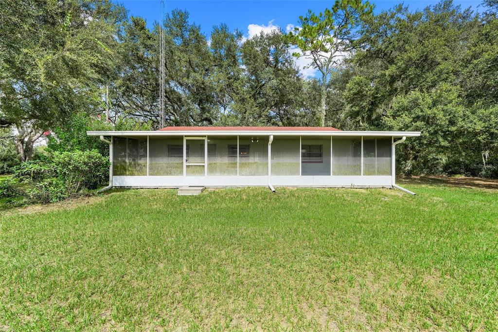 A single-story house with a full-length screened-in porch sits on a grassy lot — 1440 SELMAN ROAD, LEESBURG, FL